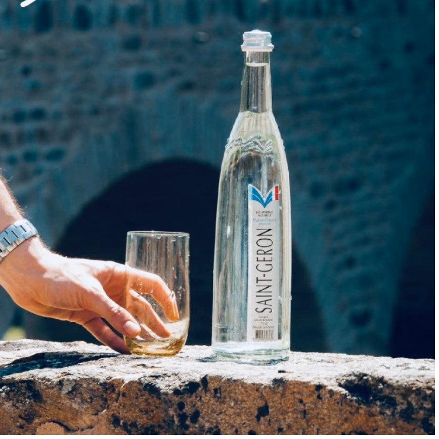 Saint-Géron bottle and glass resting near stone architecture in Auvergne, France